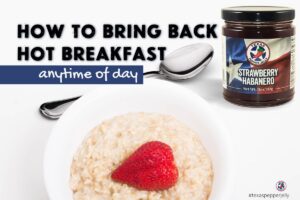 Jar of strawberry Texas pepper Jelly next to a white bowl full of oatmeal with a strawberry on top and a spoon next to it. Text how to bring back hot breakfasts anytime of day