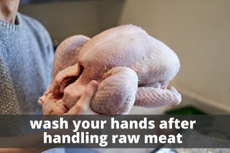 A person holding a turkey with bare hands. Wash your hands after handling raw meat.